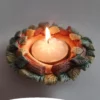 Immagine che rappresenta il portacandele artistico in ceramica "Due rami" con una candelina accesa al centro