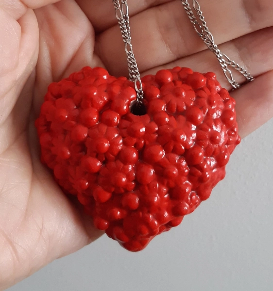 Ciondolo a cuore rosso in ceramica tenuto in una mano