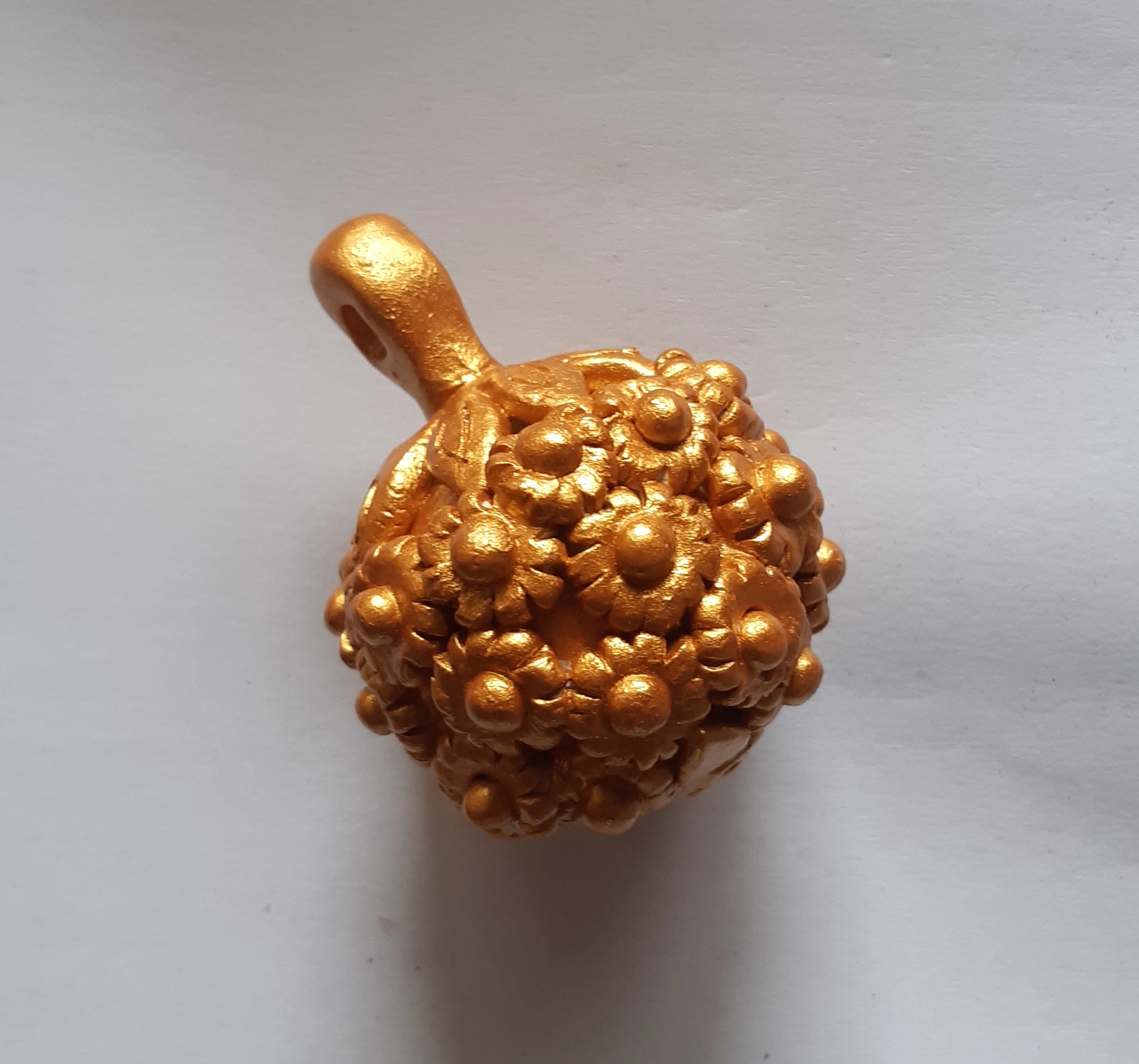 Foto di una pallina dorata in ceramica sarda per l'albero di Natale, per l'articolo L’arte sarda della ceramica incontra la lavorazione della filigrana sarda